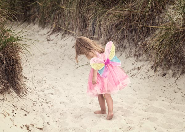 Adorable little girl wearing butterfly wings at a beach.  Photograph by Jennifer Jule Studios located in Waterford, VA.